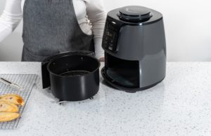 air fryer aberta numa mesa com uma pessoa atrás